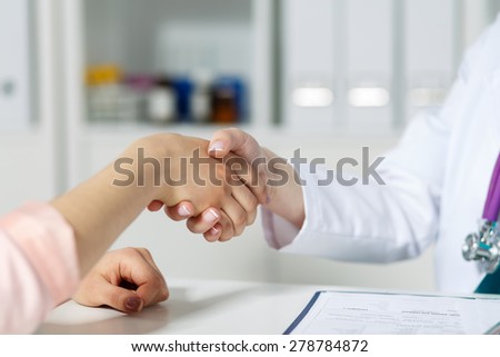 Female doctor shaking hands with patient. Partnership, trust and medical ethics concept. Handshake with satisfied client. Thankful handclasp for excellent treatment.