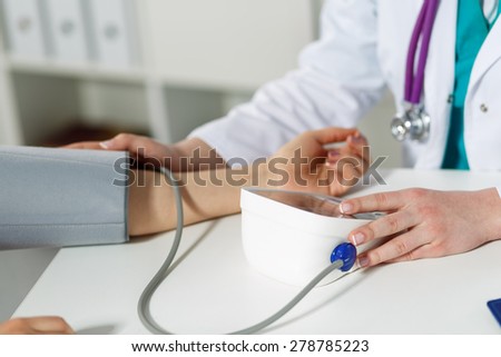 Female medicine doctor measuring blood pressure to patient. Patient communicates with physician doctor having medical examination. Medical concept. Hand of doctor and patient while pressure measuring