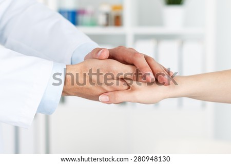 Friendly male doctor\'s hands holding female patient\'s hand for encouragement and empathy. Partnership, trust and medical ethics concept. Bad news lessening and support. Patient cheering and support