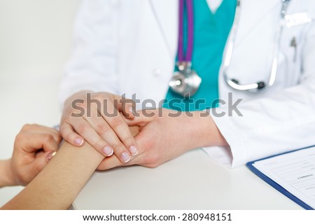 Beautiful female doctor holding patient\'s hand for encouragement and empathy and touching her arm. Partnership, trust and medical ethics concept. Bad news lessening and support. Patient cheering