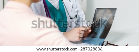 Female medicine doctor hands pointing to x-ray picture of collarbone letterbox view. Patient visiting radiologist or traumatologist concept