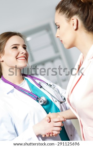 Beautiful smiling female medicine doctor shaking hands with patient. Partnership, trust and medical ethics concept. Handshake with satisfied client. Thankful handclasp for excellent treatment