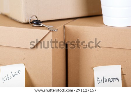 Pile of brown cardboard boxes with house or office goods. Different stuff packed in carton boxes. Moving concept. Set of cargo boxes with yellow sticker labels ready for transportation and unpacking