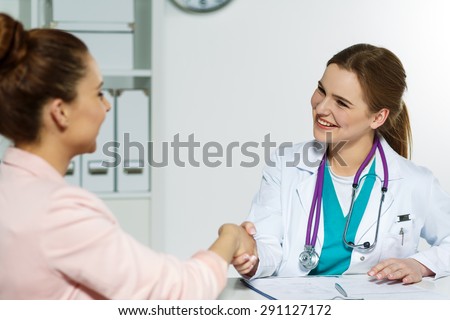 Beautiful smiling female doctor shaking hands with patient. Partnership, trust and medical ethics concept. Handshake with satisfied client. Thankful handclasp for excellent treatment.