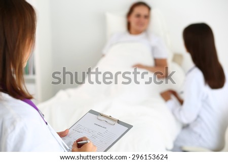 Female medicine doctor filling in patient medical history list during ward round. Medical care or insurance concept. Physician ready to examine patient and help