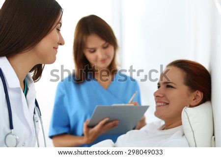 Nurse filling in patient medical history list while female medicine doctor communicating with patient during ward round. Medical care or insurance concept. Physician ready to examine and help