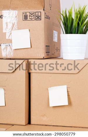 Pile of brown cardboard boxes with house or office goods. Different stuff packed in carton boxes. Moving concept. Set of cargo boxes with yellow sticker labels ready for transportation and unpacking