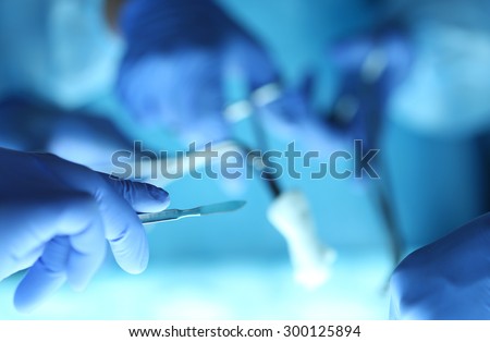 Surgeons hands holding surgical instrument while operating patient in surgical theatre. Resuscitation medicine team holding steel medical tools saving patient. Surgery and emergency concept