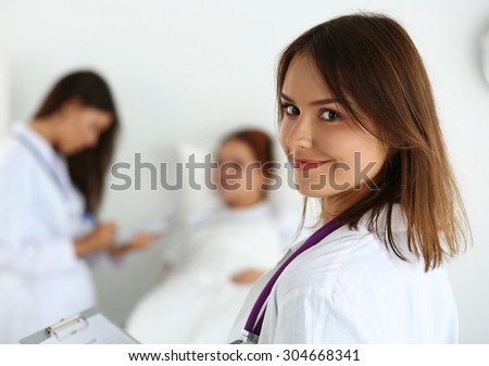 Smiling female medicine doctor filling patient medical history list during ward round while patient communicating with doctor. Health care or insurance concept. Physician ready to examine and help