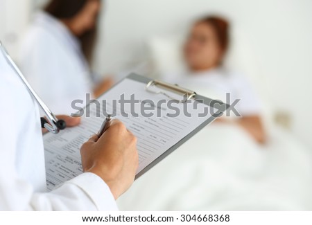 Female medicine doctor filling in patient medical history list during ward round while patient communicating with doctor. Medical care or insurance concept. Physician ready to examine and help