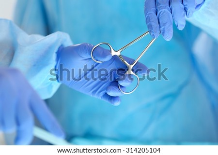 Surgeons hands holding and passing surgical instrument to other doctor while operating patient. Resuscitation medicine team holding steel medical tools saving patient. Surgery and emergency concept