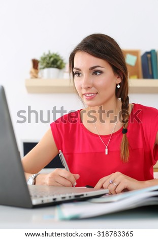 Beautiful smiling female student using online education service. Young woman in library or home room looking in laptop display watching training course. Modern study technology concept