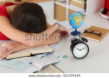 Tired female student at workplace in room taking nap on pile of textbooks. Sleepy brunette woman resting during education after sleepless night. Student in despair caused by exam deadline concept