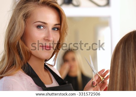 Beautiful blonde female hairdresser holding scissors in hands, picking proper hairdo to long haired customer and looking in camera. Hairdresser salon, barber shop, perfect look, new hairdo concept