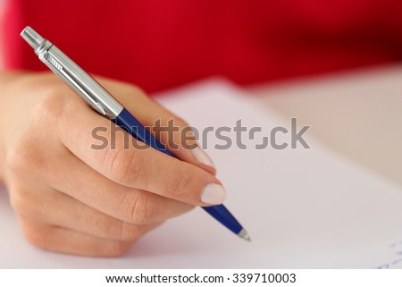 Female hand holding silver pen closeup. Woman writing letter, list, plan, making notes, doing homework. Student studying. Education, self development and perfection concept