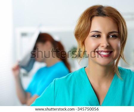 Beautiful female medicine doctor laughing on her colleague examining x-ray picture mistake. Radiology, traumatology, medical care or insurance, education, stress, interns concept