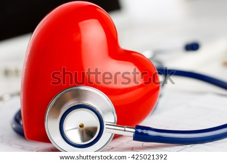 Medical stethoscope head and red toy heart lying on cardiogram chart closeup. Cardio therapeutist, pulse graph, cardiac physical, heart rate measure, arrhythmia, 911, er and resuscitation concept