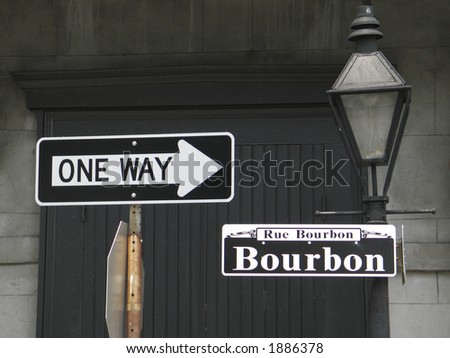 \'one way\' sign pointing to Bourbon St. sign