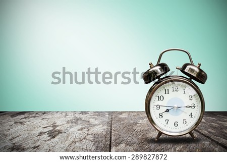 Retro alarm clock on desk front mint green wall background
