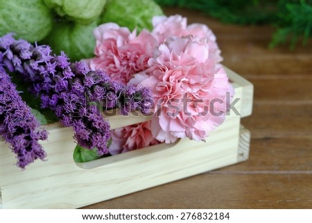 Pink Carnation and purple flowers in light color wood tray