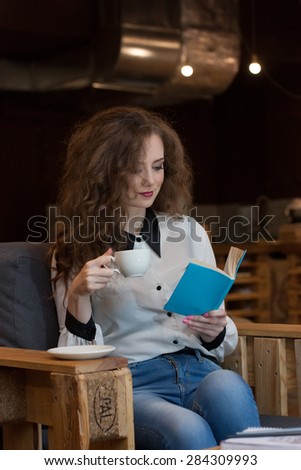 Beautiful girl with coffee reading a book in a coffee shop