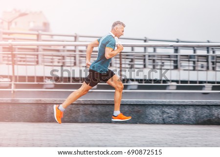 healthy lifestyle middle aged man runner running upstairs on city bridge road. Motion shot