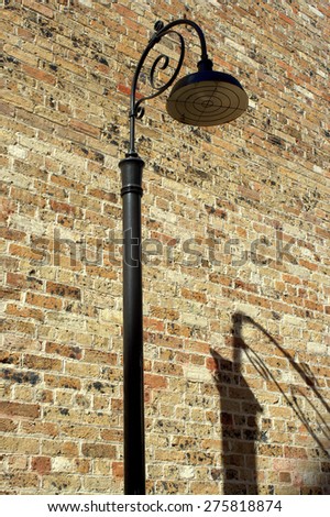 a street lamp and its shadow by an old brick wall on a lane in the Rocks, Sydney