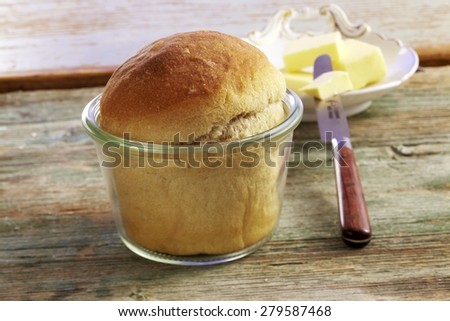 close up of small bred rolls / loaves of white bread on wooden surface with knife and butter