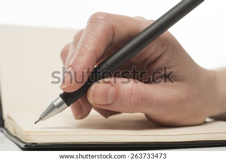 Female hand writing in notebook, isolated on white