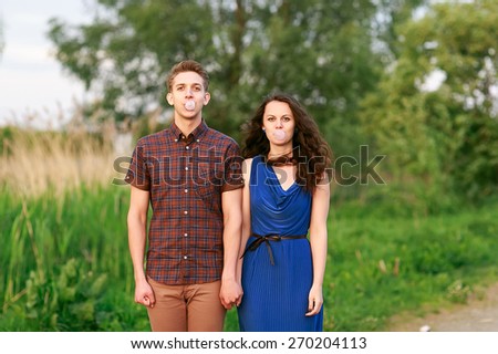 young couple blowing bubbles with chewing gum.