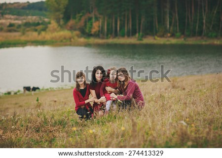 sweet smily family photo, taken by the lake, of mother and her three daughters, all four wearing red outfits