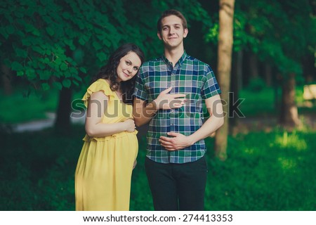Happy parents-to-be are walking down the forest path, pregnancy photo
