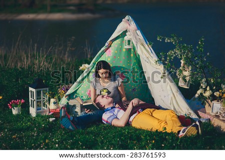 happy couple is reading the book in the tent in summer