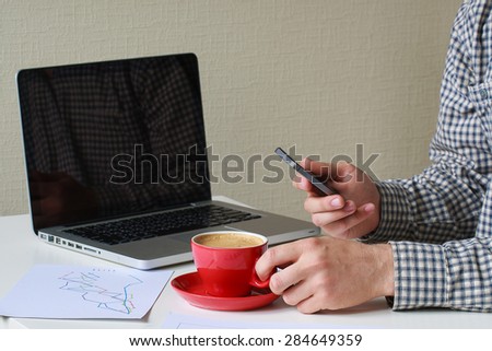 office worker is sitting at a laptop with coffee and making phone call