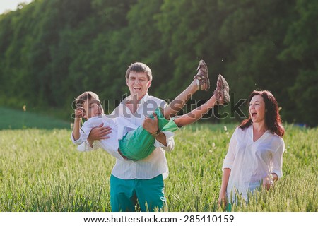 a happy family is having fun, a father is lifting his son into the air