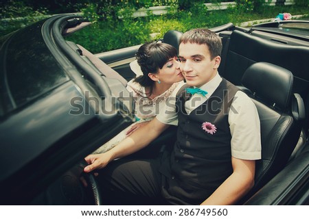 a happy married couple is sitting and kissing in the car