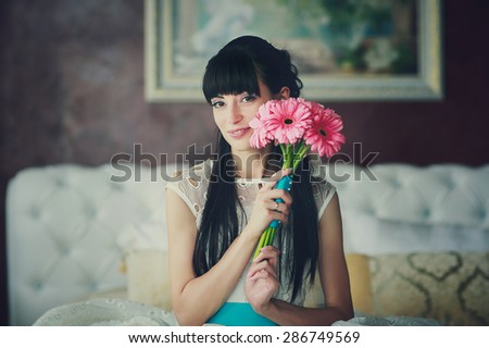 a happy bride is sitting on the white sofa with flowers in her hands