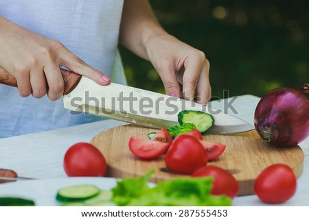 Green diet, a woman cut cucumbers. Hands woman standing in the kitchen while slicing cucumber