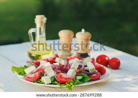 Greek salad with olive oil and some spices on a white wooden table