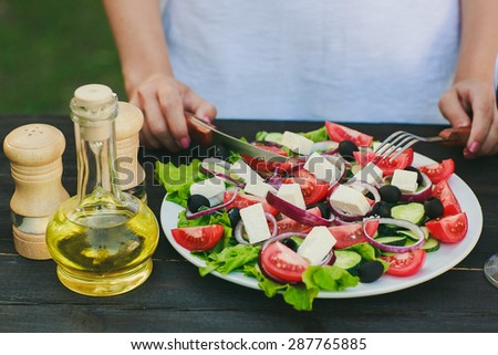 a chef is trying Geek salad, olive oil, there are spices and wine on the table
