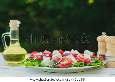 Greek salad, olive oil and spices on a white wooden table