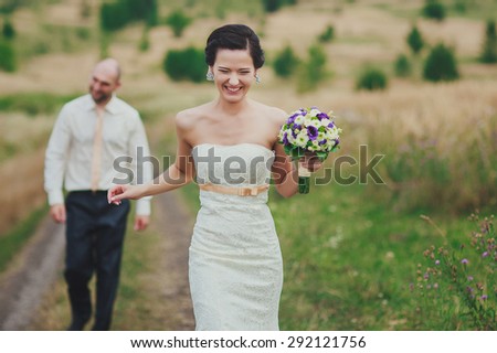 a bride is walking from a groom down a field path