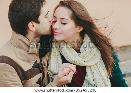a boy is holding his girlfriend\'s hand and kissing her on a cheek, close up photo
