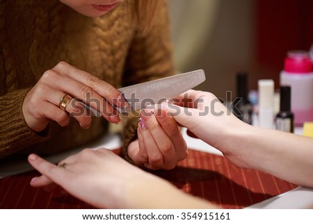 a manicure master is filing nails of her client