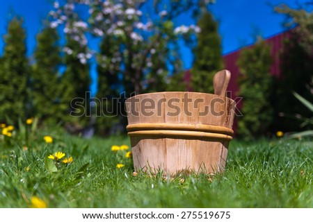Wooden bucket for sauna on green grass in spring garden