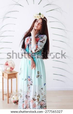 Gorgeous woman in spring dress and floral crown near the wall