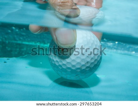 Golf ball and your hand in the water for background.