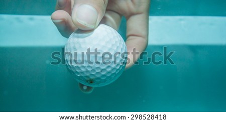 Golf ball and your hand in the water for background.