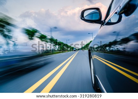 Side view of black car driving on the country road.