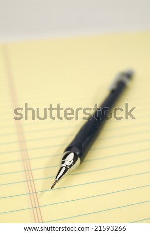 Blue mechanical pencil on a yellow legal pad. Focus on the tip of the pencil.